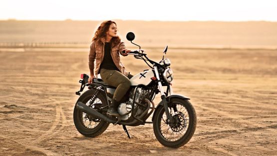 A rider sitting proudly on a vintage motorcycle.