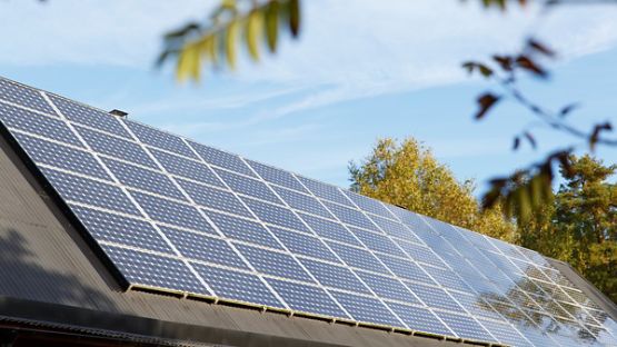 A cottage that has been outfitted with solar panels in a pristine natural environment.